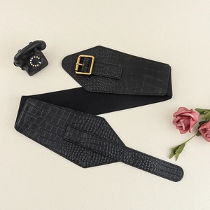 Detail of wide black faux leather belt with crocodile texture and gold buckle