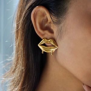 Close-up of gold drip-style lip earrings with polished metallic finish on a female model
