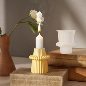 Modern yellow striped resin candle holder with a lit white candle on a wooden display stand