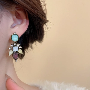 Close-up of vintage drop earrings with colorful zircon stones on gold-plated metal base