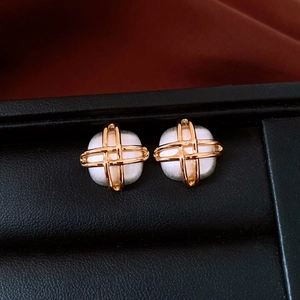 Macro view of square earrings with white gemstone and golden cross-wire detail