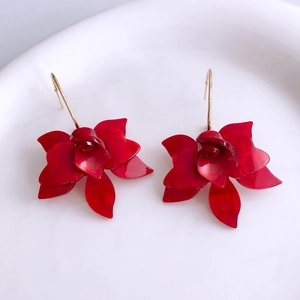 Détail de boucles d'oreilles fleurs en résine rouge foncé avec pétales brillants