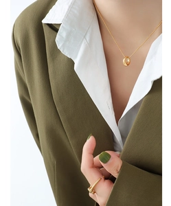 Detail view of 18K gold plated oval pendant necklace on a model with minimalist nail ring
