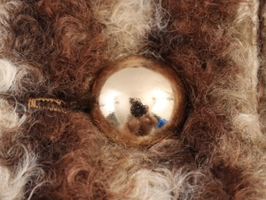 Gros plan d'un bouton doré sphérique sur le tissu en fausse fourrure marron et beige