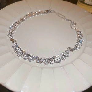 Elegant silver teardrop necklace with shimmering zircon stones on a white ceramic plate