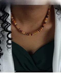 Detail einer Perlenkette mit erdigen Abakusperlen und goldenen Metall-Abstandshaltern am Model