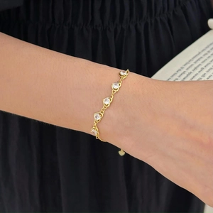 Close-up of golden heart-shaped S925 silver bracelet with sparkling zircon on wrist