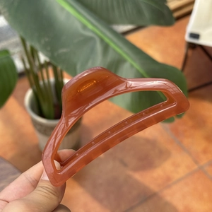 Detail of a 10cm amber perfume bottle hair claw clip made of translucent resin