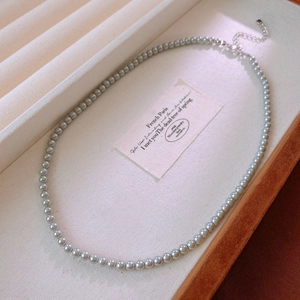 Detailed view of grey pearl necklace with silver extension chain on a velvet tray