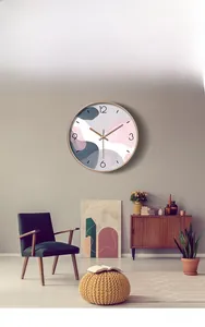 Modern abstract round wall clock on a light grey wall above a green velvet chair