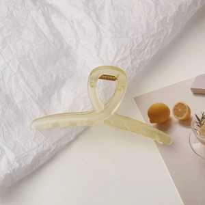 Détail d'une grande pince à cheveux jaune givré avec un design torsadé élégant