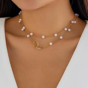 Detail of layered pearl necklace with interlocking gold rings on model neck