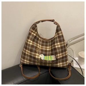 Detail showing brown plaid tote bag with dog embroidery and leather shoulder strap