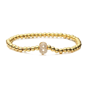 Macro detail of gold beaded stretch bracelet with cubic zirconia letter B pendant