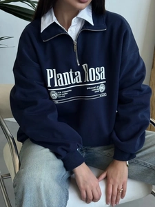 Detail of the navy blue half-zip hoodie featuring white letter print and ribbed cuffs
