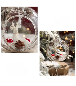 Macro detail of glass Christmas ball with white deer, red mushrooms and pine cone scene
