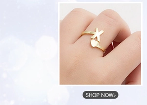 Detail of adjustable gold ring featuring X-shape and heart design on finger