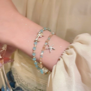 Detailansicht des zweilagigen Perlenarmbands mit Silberdelfin- und Seesternanhängern
