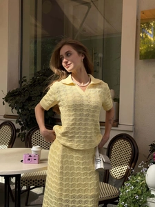 Detail of yellow hollow knit polo top and matching skirt with delicate floral patterns