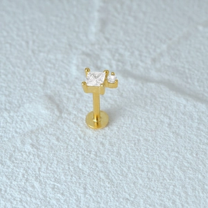 Macro shot of gold cartilage stud featuring clear square and round inlaid gemstones