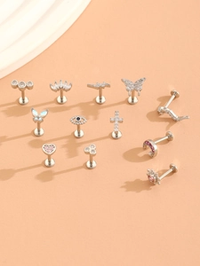 Macro shot of silver body jewelry pieces with crystal heart, butterfly and crown charms
