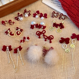 Flat lay of red velvet bow earrings with pearls and festive golden pendants