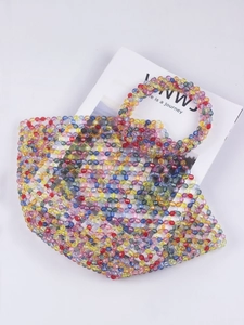 Detail of colorful acrylic beaded handbag with hollow weave placed on a magazine
