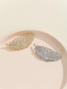 Detailed view of gold and silver feather brooches with micro-set shimmering cubic zirconia