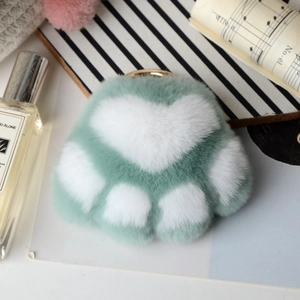 Close-up of mint green plush cat paw keychain with soft fur and gold metal ring