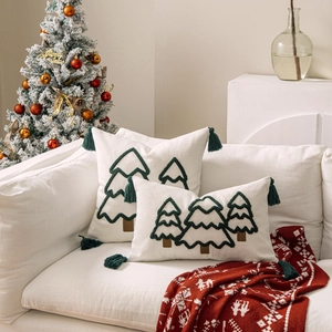 Detail von Kissenbezügen mit Weihnachtsbaummuster und grünen Quasten auf einem Sofa