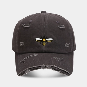 Detail of gray distressed baseball cap featuring vintage frayed holes and bee embroidery