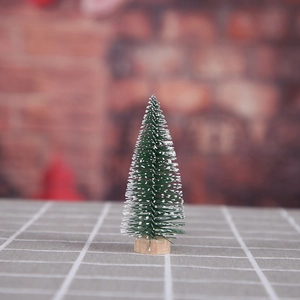 Miniature Christmas tree with white frosted snow on green pine needles and wood base