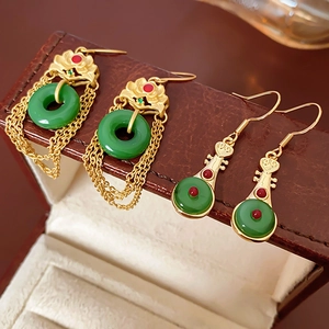 Detail of gold plated lotus and pipa earrings with green jade and elegant long tassels
