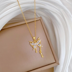 Elegante collana a farfalla dorata con cristalli trasparenti su sfondo di seta bianca lussuosa