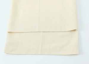 Gros plan sur tissu tissé crème montrant une couture plate et la finition d'un ourlet doublé