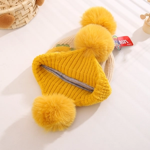 Macro view of warm knit winter baby hat featuring soft lining and large fluffy yellow pom-poms