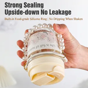 Leak-proof glass water bottle with floral sleeve and pearl handle shown upside down