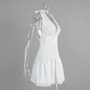 Detail of polka dot halter mini dress featuring deep V-neck and pleated elastic waistline
