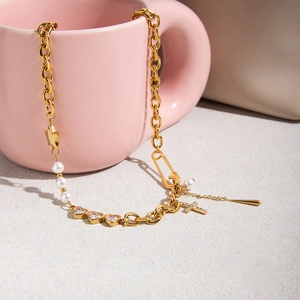 Détail d'un collier doré avec zircons en cœur, perles et croix suspendue sur une tasse