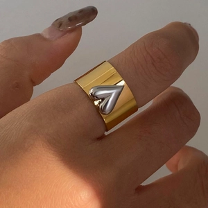 Close-up of wide gold stainless steel ring with a 3D silver heart on a model hand