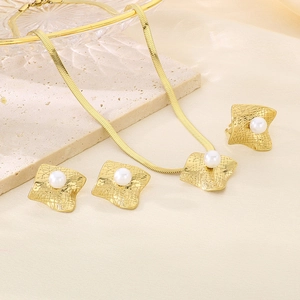 Detailed macro of gold plated geometric jewelry set with pearls on silk fabric