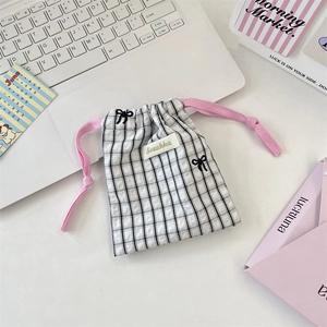 Detail of fabric drawstring pouch with black gingham pattern and pink bow embroidery