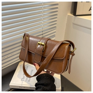 Close-up of brown vintage leather shoulder bag with metallic buckle on white pedestal