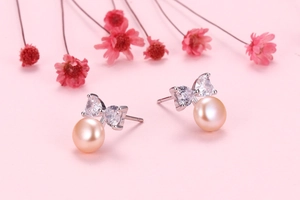 Detailed close-up of bow-knot pearl earrings with champagne freshwater pearls and zircon