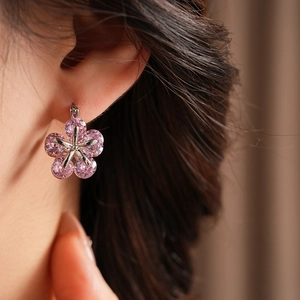 Gros plan d'une boucle d'oreille fleur en zircon rose avec base en métal argenté