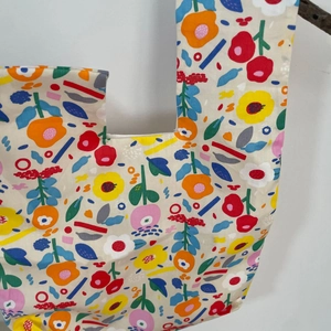 Detail of floral printed canvas wrist bag showing colorful flower patterns on beige cotton
