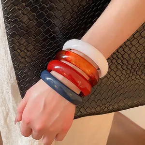 Set of four colorful resin bangles in white, amber, red, and blue for a modern look