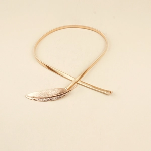 Close-up of golden metallic elastic waist chain featuring a detailed leaf buckle design