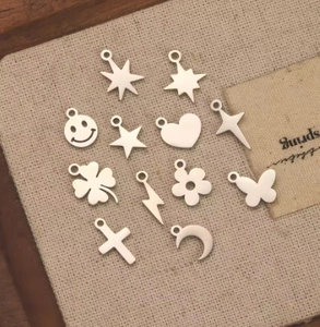Flat lay of mixed silver stainless steel DIY pendants including stars, hearts and moon shapes