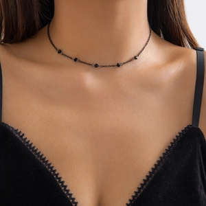 Close-up of a gothic black beaded choker with delicate tassels worn on a lace neckline